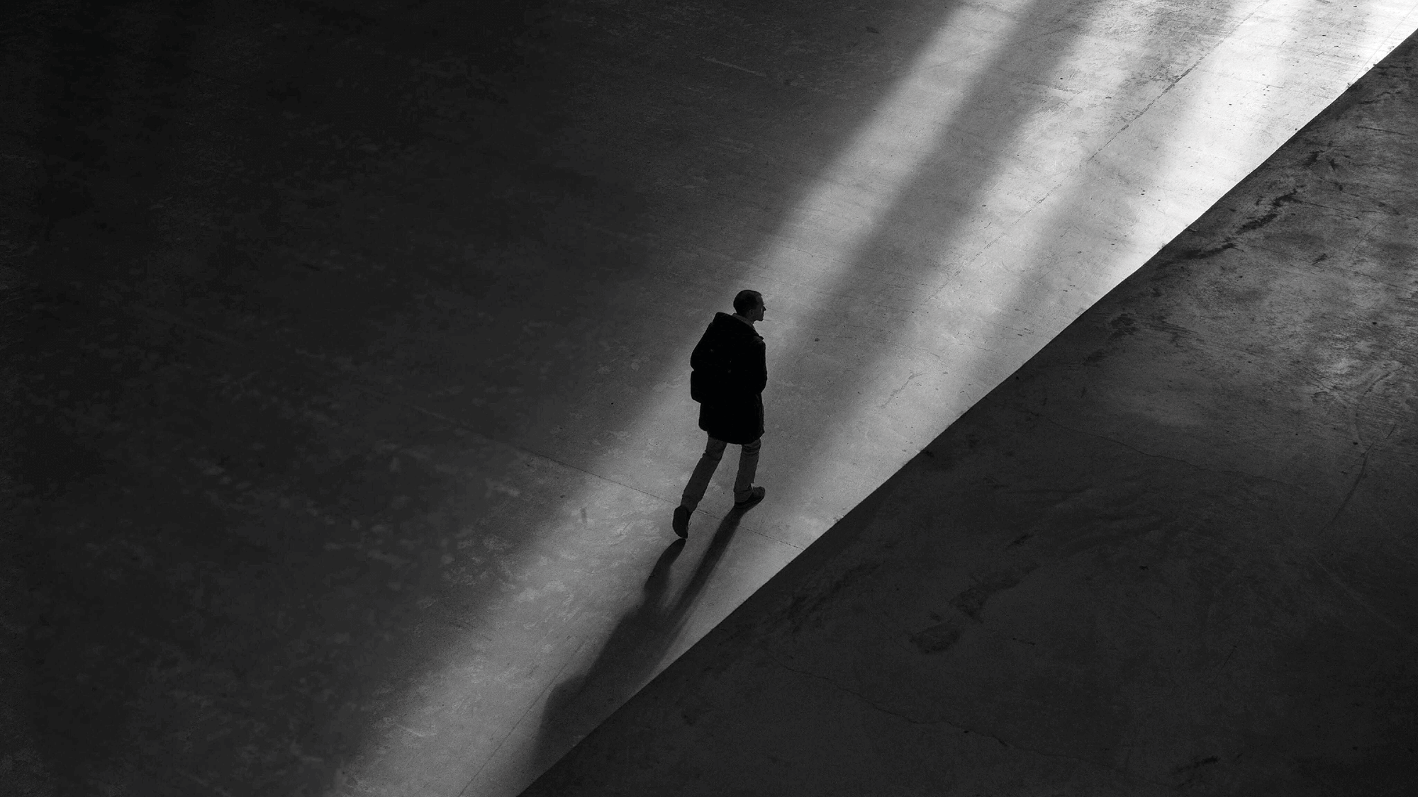 Person geht allein über einen Platz mit langem Schatten