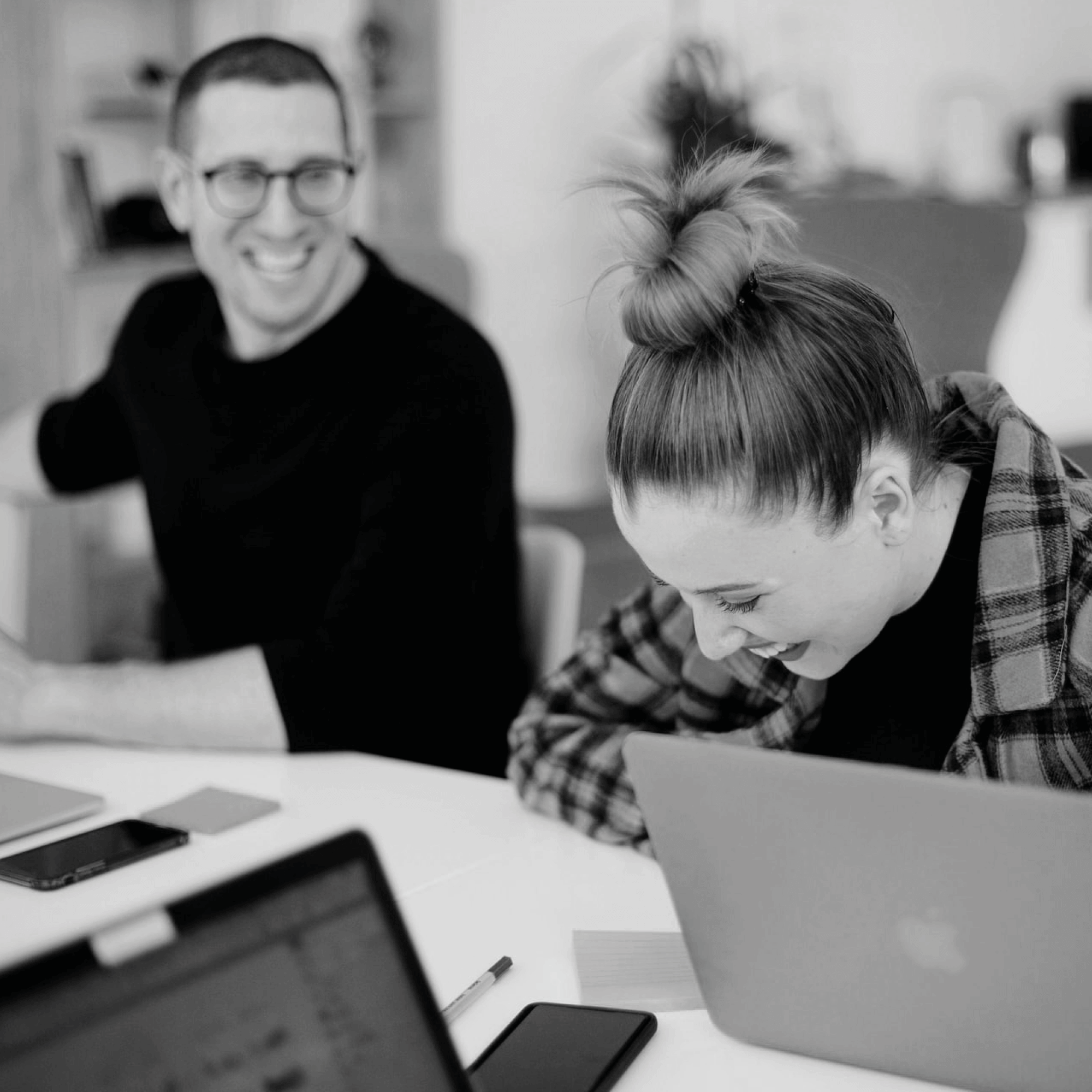 Zwei Menschen lachen gemeinsam am Laptop